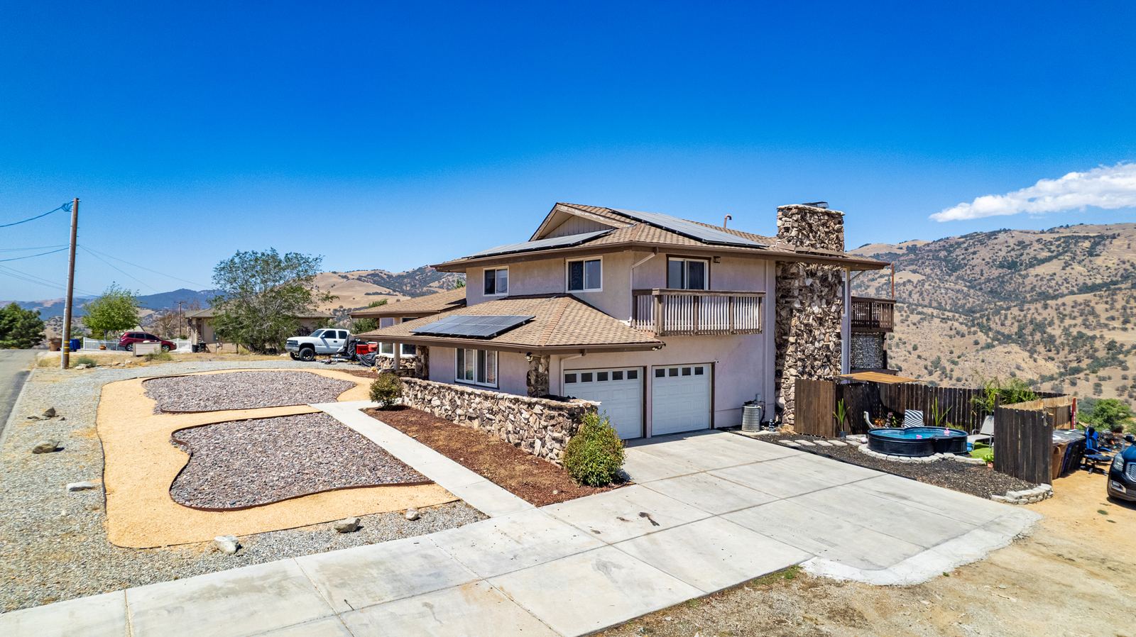 Side exterior with attached garage, stone chimney, upper balcony and owned solar
