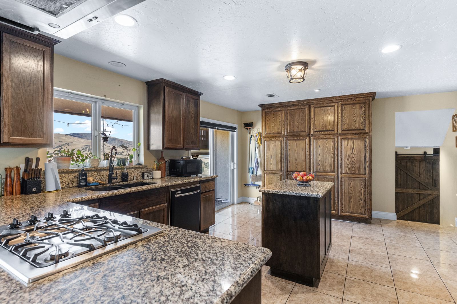 Kitchen with granite counters, gas cooktop, oak cabinetry and a garden window facing the hills