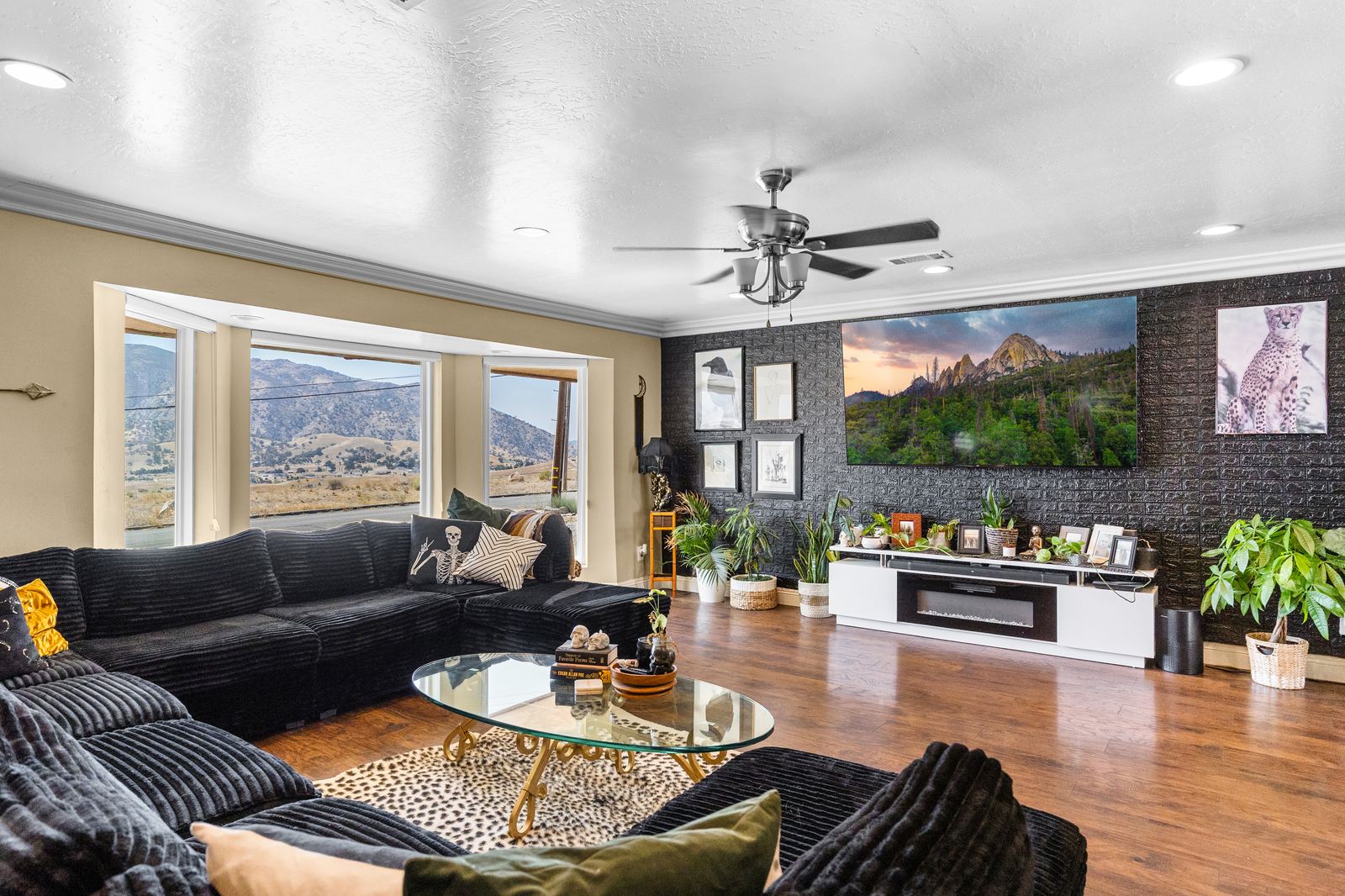 Main living room with bay-window mountain views, hardwood floors, crown molding and a media accent wall